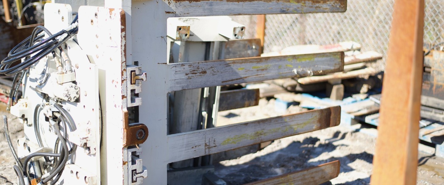 A scratched-up lift attachment piece that's sitting in a lot